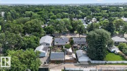 Aerial view showcasing a residential property with a detached garage, established perimeter fencing, and a surrounding tree-lined neighborhood - 