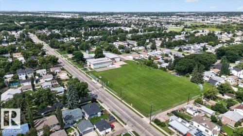 Expansive aerial showcasing a residential neighborhood with established trees, paved roads, and a large green recreational field - 11934 43 Street Nw, Edmonton, AB - Outdoor With View