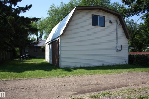 Two-story outbuilding featuring light-colored siding, a brown trim, and a metal roof - 5227 51 Street, Redwater, AB - Outdoor With Exterior