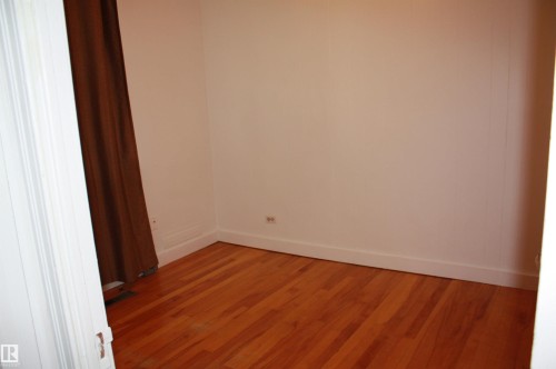 Hardwood flooring in a neutral-toned room with white baseboards and trim - 5227 51 Street, Redwater, AB - Indoor Photo Showing Other Room