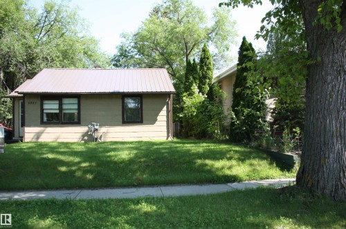 Front exterior featuring a metal roof, horizontal siding, and a manicured lawn - 5227 51 Street, Redwater, AB - Outdoor