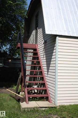 Exterior structure featuring light-colored horizontal siding and a gambrel roofline with corrugated metal - 5227 51 Street, Redwater, AB - Outdoor
