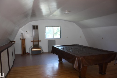 Spacious bonus room featuring an arched ceiling, wood-finish flooring, and natural light from a double window - 5227 51 Street, Redwater, AB - Indoor Photo Showing Other Room