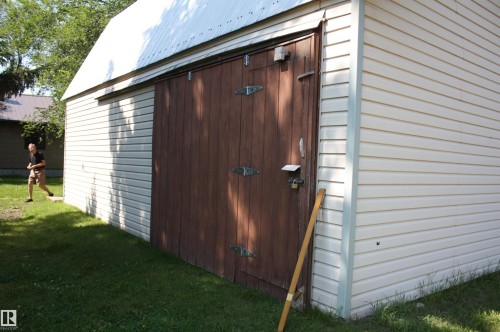 Detached outbuilding featuring a metal roof and light-toned horizontal siding - 5227 51 Street, Redwater, AB - Outdoor With Exterior