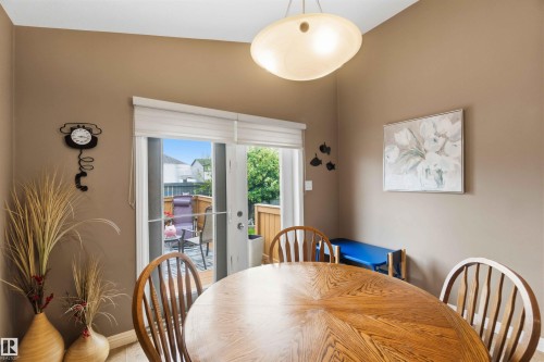 Dining area featuring wood-finish flooring, a contemporary ceiling light fixture, and double patio doors opening to an outdoor deck - 6320 166 Avenue Nw, Edmonton, AB - Indoor Photo Showing Dining Room