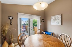 Dining area featuring wood-finish flooring, a contemporary ceiling light fixture, and double patio doors opening to an outdoor deck - 