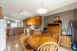 Kitchen featuring tile flooring, wooden cabinetry, and white appliances - 