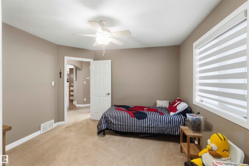 Carpeted room featuring a ceiling fan with integrated lighting, a window with horizontal blinds, neutral wall paint, and white trim - 6320 166 Avenue Nw, Edmonton, AB - Indoor Photo Showing Bedroom