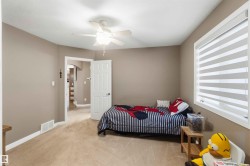 Carpeted room featuring a ceiling fan with integrated lighting, a window with horizontal blinds, neutral wall paint, and white trim - 