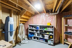 Utility area featuring exposed wood framing, an open wood staircase, and a visible central vacuum system - 