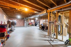 Unfinished basement featuring exposed wood joists and structural framing - 