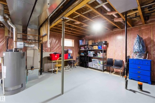 Unfinished basement offering exposed ceiling joists, insulated walls, concrete flooring, a water heater, and a furnace unit - 6320 166 Avenue Nw, Edmonton, AB - Indoor Photo Showing Basement