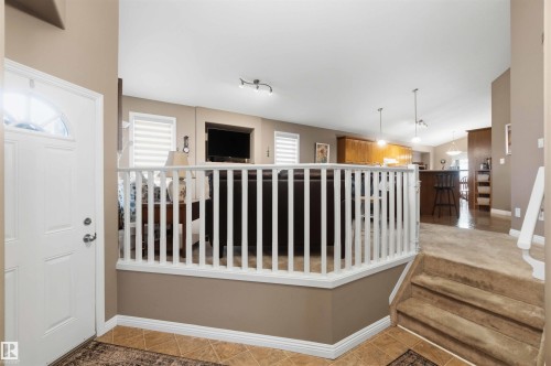 Entryway featuring tile flooring, a white paneled door with an arched glass insert, and a partial carpeted staircase - 6320 166 Avenue Nw, Edmonton, AB - Indoor Photo Showing Other Room
