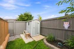 Private backyard featuring a gray storage shed on a concrete pad, surrounded by a combination of wood and painted fencing - 