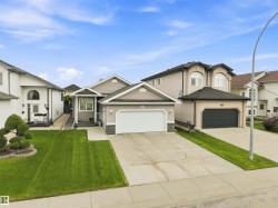 Exterior featuring light gray siding, a stone facade accent, and a front-facing attached two-car garage - 