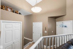 Foyer featuring a vaulted ceiling with a semi-flush mount fixture, a decorative ledge, white paneled doors, and a staircase with a white railing - 