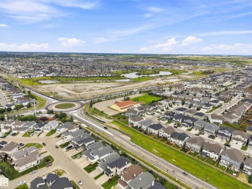 Aerial perspective showcasing a residential development with multiple single-family homes, a prominent roundabout, and roadways - 6320 166 Avenue Nw, Edmonton, AB - Outdoor With View