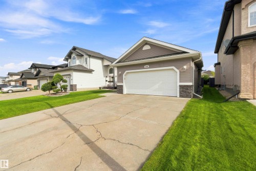 Contemporary exterior featuring horizontal siding, stone veneer accents, an attached garage with a white door, and a concrete driveway - 6320 166 Avenue Nw, Edmonton, AB - Outdoor