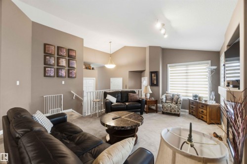 Spacious living area featuring vaulted ceilings, track lighting, and a stone-clad fireplace - 6320 166 Avenue Nw, Edmonton, AB - Indoor Photo Showing Living Room