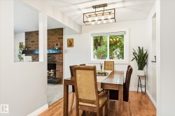 Dining area featuring wood-finish flooring, a white window frame, and a contemporary linear chandelier - 
