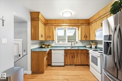 Kitchen featuring wood-finish cabinetry, light-colored wood-finish flooring, and a window with skylights - 