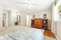 Bright room featuring wood-finish flooring, a ceiling fan with integrated lighting, and multiple windows with white trim - 