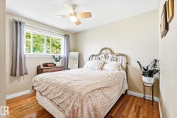 Bedroom featuring wood-finish flooring, a multi-pane window, and a ceiling fan with integrated lighting - 