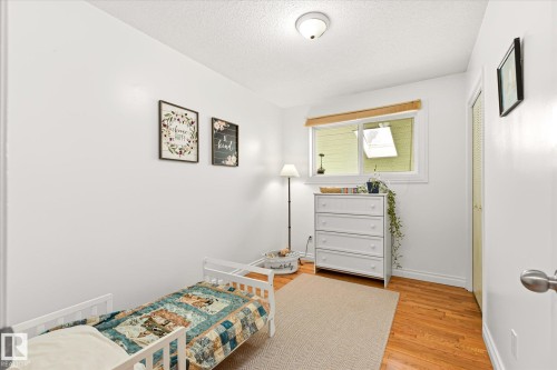 Bright room featuring a window with wood-finish trim, a flush-mount ceiling light, wood-finish flooring, and a bifold closet door - 4921 47 Avenue, Legal, AB - Indoor Photo Showing Bedroom