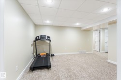 Finished lower level featuring recessed lighting, a drop ceiling, light-toned carpeting, painted walls, and white trim - 