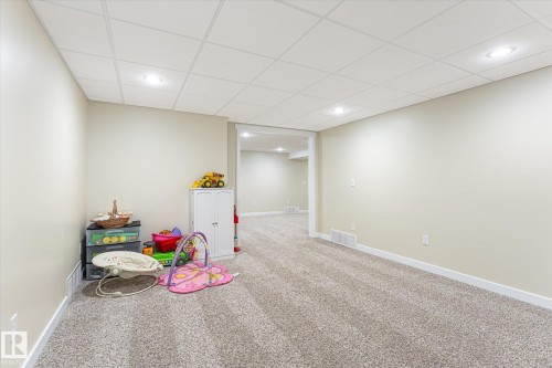 Spacious room featuring neutral carpeting, light-toned walls, recessed lighting, and a white grid ceiling - 4921 47 Avenue, Legal, AB - Indoor