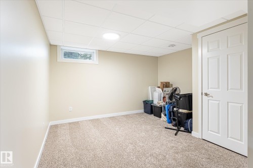 Carpeted room featuring a drop ceiling with recessed lighting, a horizontal window, and a paneled white door - 4921 47 Avenue, Legal, AB - Indoor