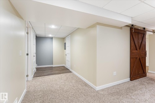 Finished lower level featuring neutral carpeting, recessed lighting, white trim, a barn door, and wood-finish flooring - 4921 47 Avenue, Legal, AB - Indoor