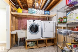 Dedicated laundry area featuring a front-load washer and dryer, utility sink, and overhead shelving - 