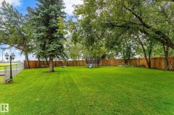 Expansive green lawn surrounded by mature trees and a wood privacy fence - 