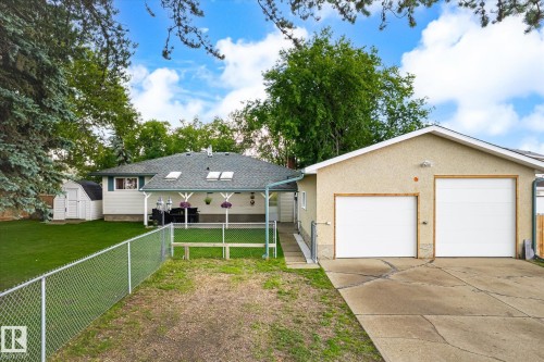 Rear exterior featuring a covered patio, skylights, and a detached two-car garage with white overhead doors - 4921 47 Avenue, Legal, AB - Outdoor