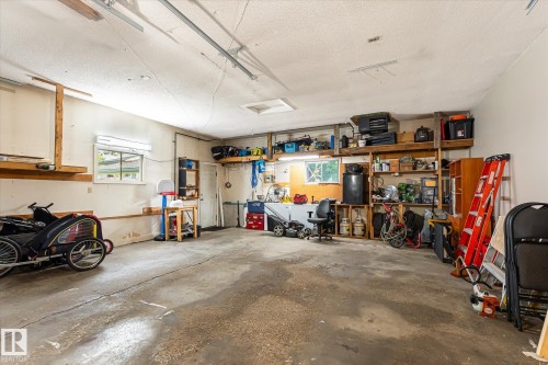Spacious garage featuring a concrete floor, built-in shelving, a window providing natural light, a utility door, and overhead lighting - 4921 47 Avenue, Legal, AB - Indoor Photo Showing Garage