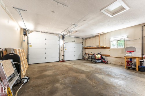 Attached two-car garage with concrete flooring, two automatic overhead doors, and built-in wall shelving - 4921 47 Avenue, Legal, AB - Indoor Photo Showing Garage