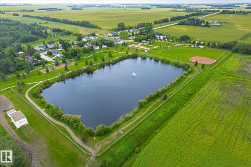 Aerial perspective showcasing a community park with a prominent pond and fountain feature - 4921 47 Avenue, Legal, AB - Outdoor With Body Of Water With View