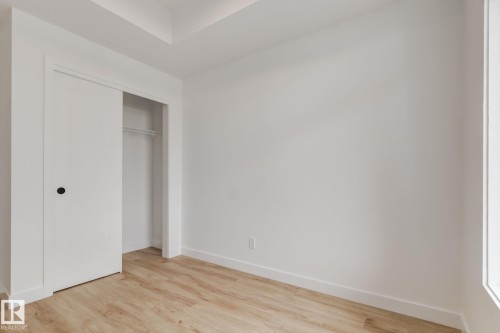 Room featuring light wood-finish flooring, white walls, and a sliding closet door with a black knob - #1 16231 19 Av Sw, Edmonton, AB - Indoor Photo Showing Other Room