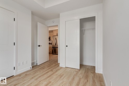 Light wood-finish flooring throughout, complemented by crisp white walls and trim - #1 16231 19 Av Sw, Edmonton, AB - Indoor Photo Showing Other Room