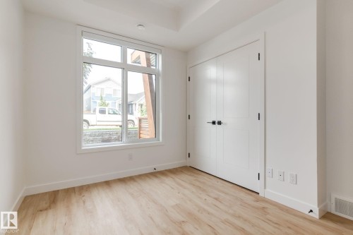 Contemporary room featuring light wood-finish flooring, white walls, and a large multi-pane window - #1 16231 19 Av Sw, Edmonton, AB - Indoor Photo Showing Other Room
