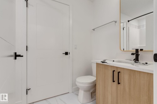 Contemporary bathroom vanity with a wood-finish cabinet, white countertop, and matte black faucet - #1 16231 19 Av Sw, Edmonton, AB - Indoor Photo Showing Bathroom