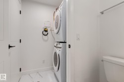 Dedicated laundry area featuring a stacked washer and dryer, white walls, and marble-patterned floor tiling - 