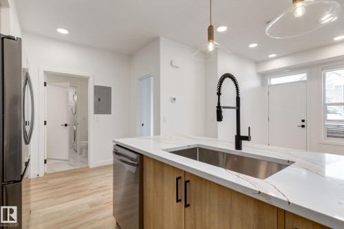 Kitchen island with a stainless steel sink and matte black gooseneck faucet - #1 16231 19 Av Sw, Edmonton, AB - Indoor Photo Showing Kitchen