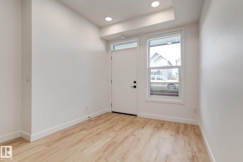 Entryway featuring wood-finish flooring, a white door with matte black hardware, and a single pane window - #1 16231 19 Av Sw, Edmonton, AB - Indoor Photo Showing Other Room