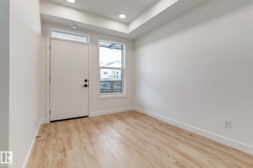 Entry with a contemporary door and transom window, wood-finish flooring, recessed lighting, and crisp white walls - #1 16231 19 Av Sw, Edmonton, AB - Indoor Photo Showing Other Room