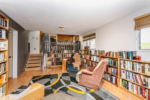 Open-concept living space featuring wood-finish flooring, multiple built-in bookcases, and a multi-level design - 18316 78 Avenue Nw, Edmonton, AB - Indoor