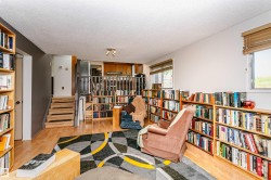 Open-concept living space featuring wood-finish flooring, multiple built-in bookcases, and a multi-level design - 