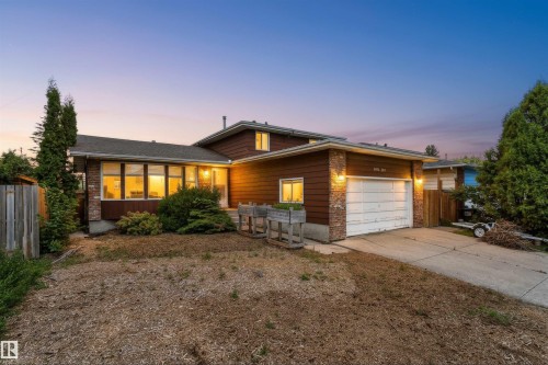Split-level home featuring a two-car garage with concrete driveway, brick accents, and horizontal siding - 18316 78 Avenue Nw, Edmonton, AB - Outdoor