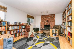 Living area featuring a brick fireplace with a black hearth, track lighting, and built-in shelving - 
